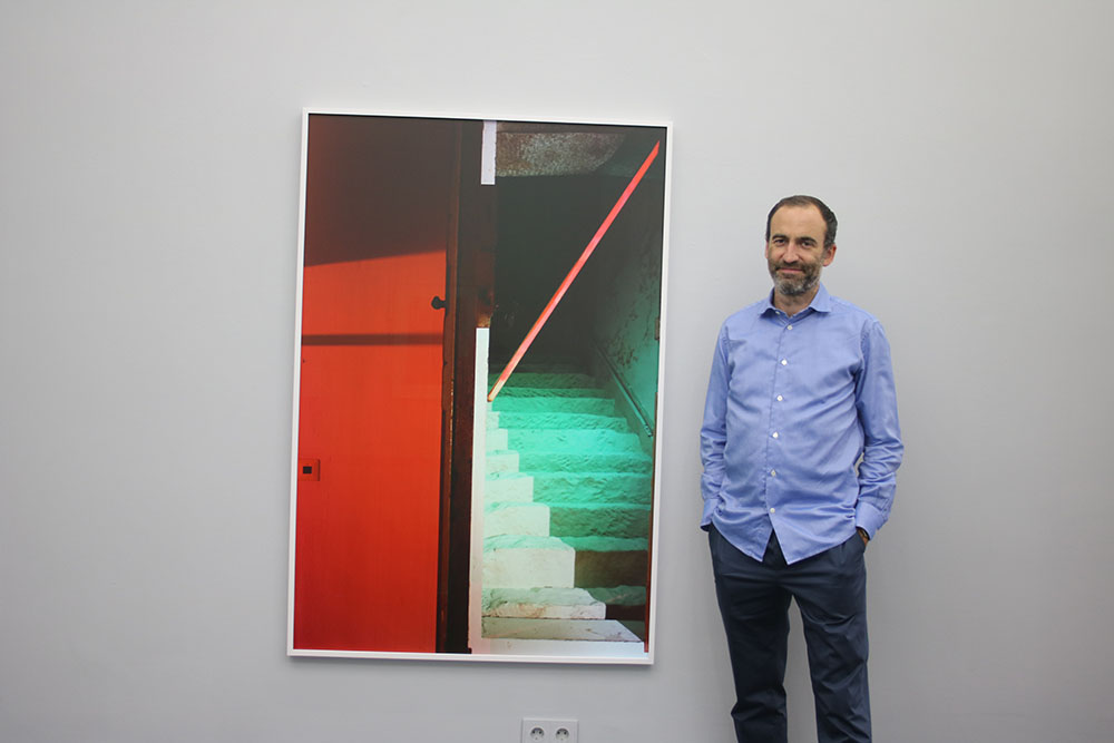 Galerist Daniel Schierke vor einer Fotografie von Andrea Grützner